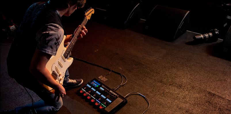 A guitarist bends over to operate the G11.